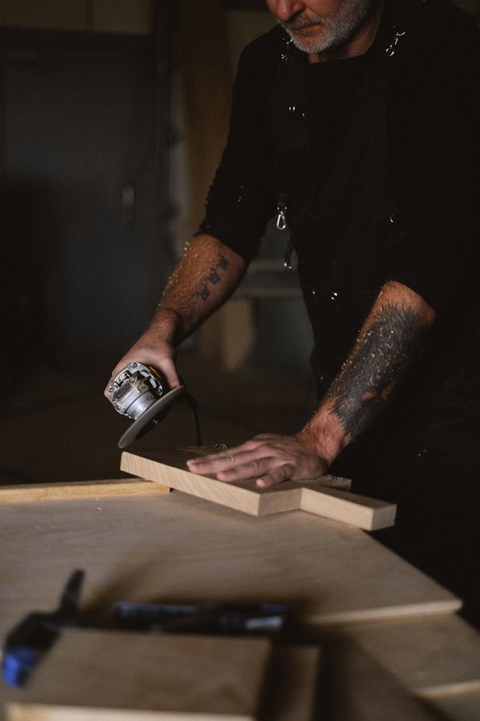 Home A focused craftsman polishing wood with a grinder in his workshop, showcasing professional skill and technique.