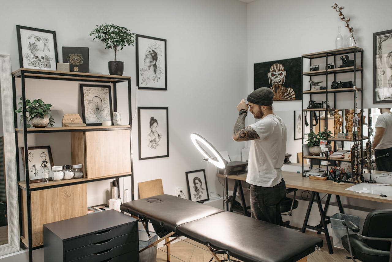 About A tattoo artist in a modern studio, surrounded by artworks and tattoo equipment.